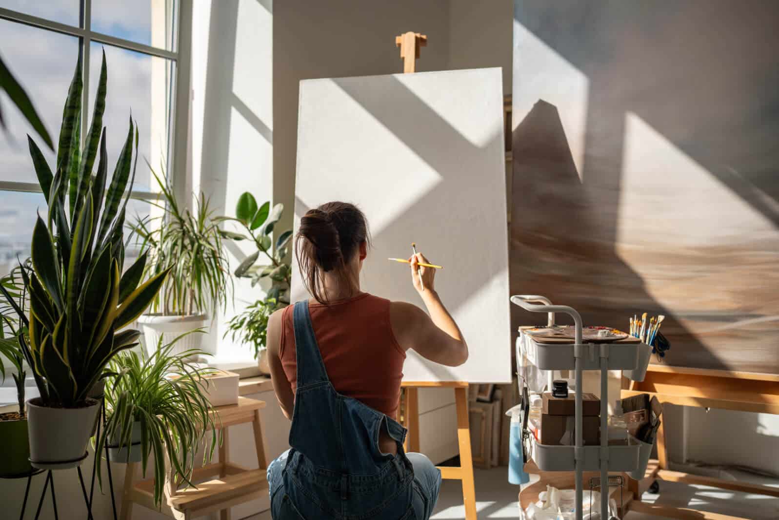 Creative Artist Woman Starts To Draw Artwork On New White Canvas On Easel With Brush At Equipped Modern Art Studio Interested Talented Girl Painter Enjoy Creative Hobby For Soul In Painter W